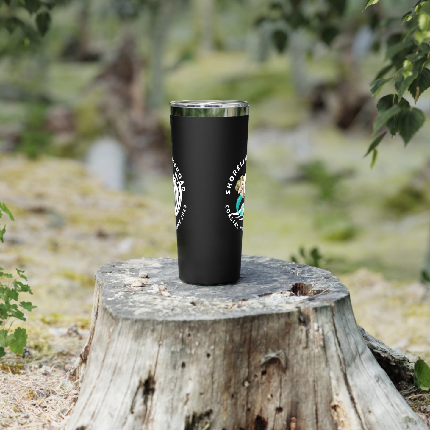 a black tumbler cup sitting on top of a tree stump