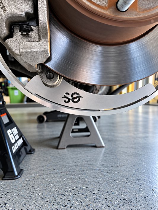 Close-up of the lower arc of a Shoreline Offroad 2N1 wheel light bracket with the SO logo, beside a brake disc and caliper