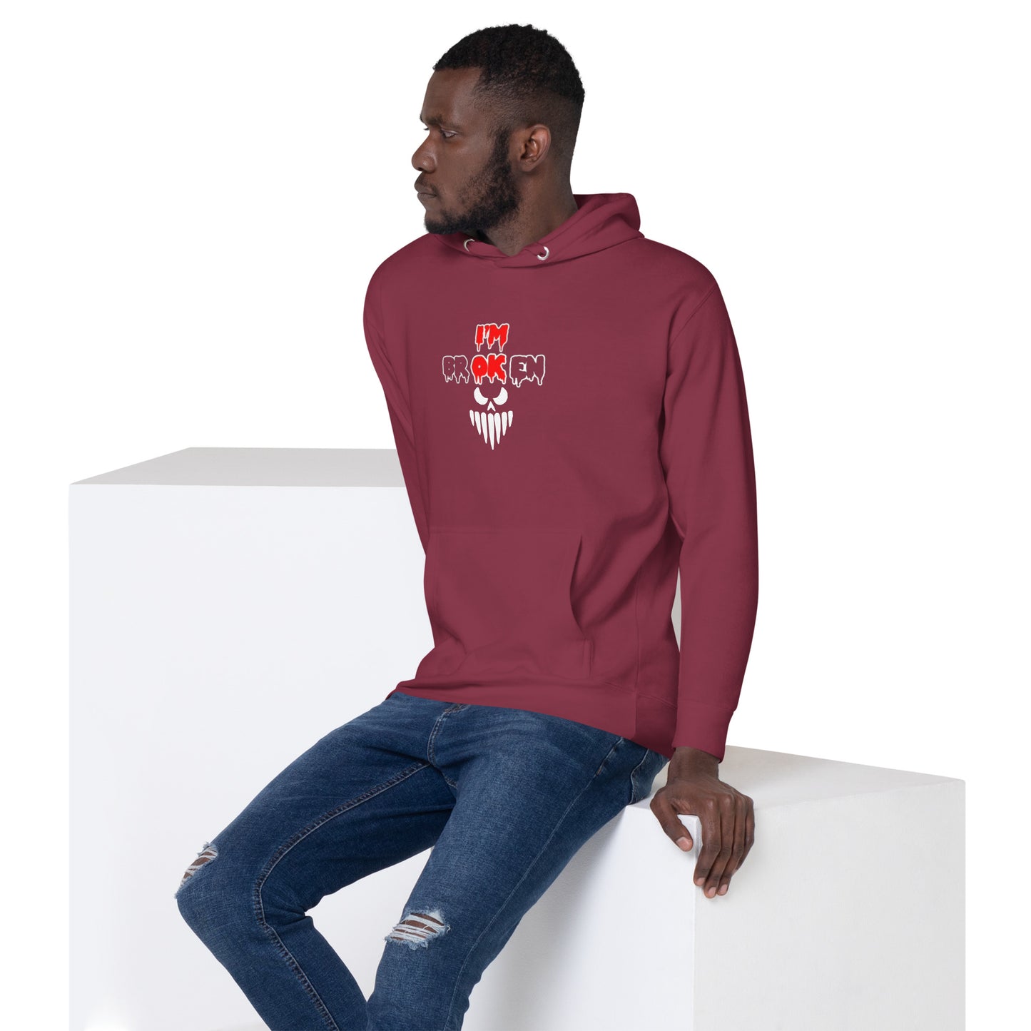 a man sitting on a block wearing a maroon hoodie
