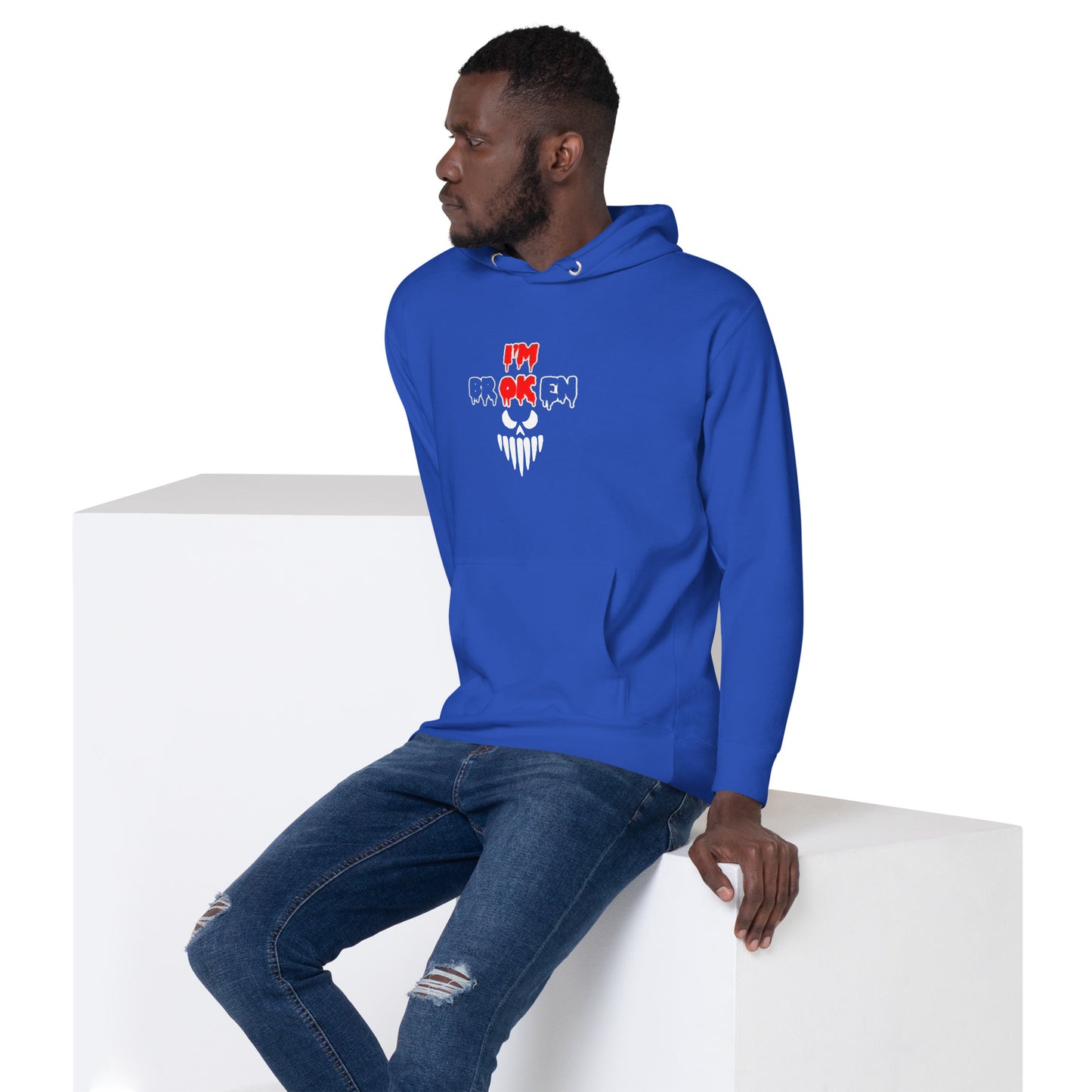 a man in a blue hoodie sitting on a white block
