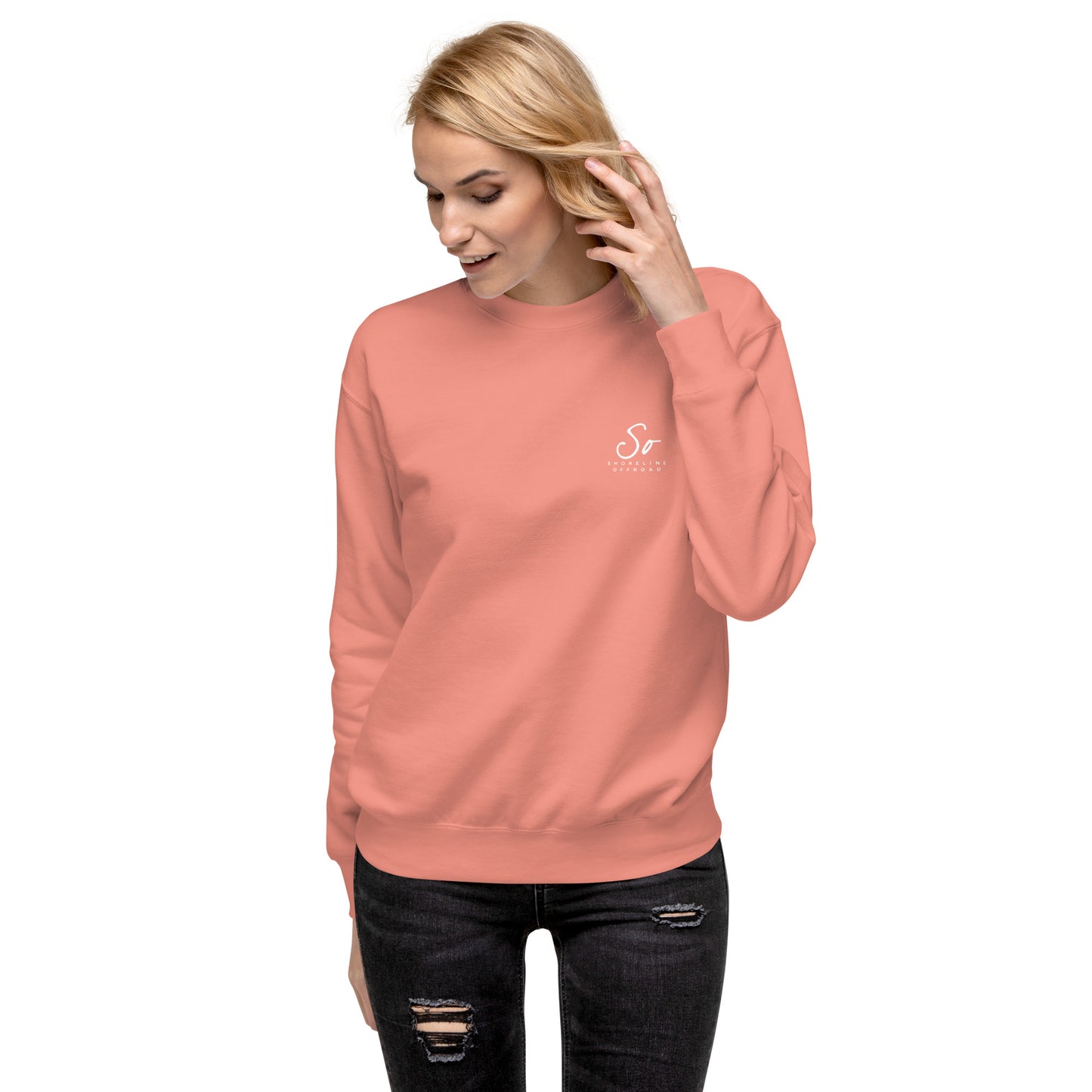 a woman wearing a pink sweatshirt and ripped jeans
