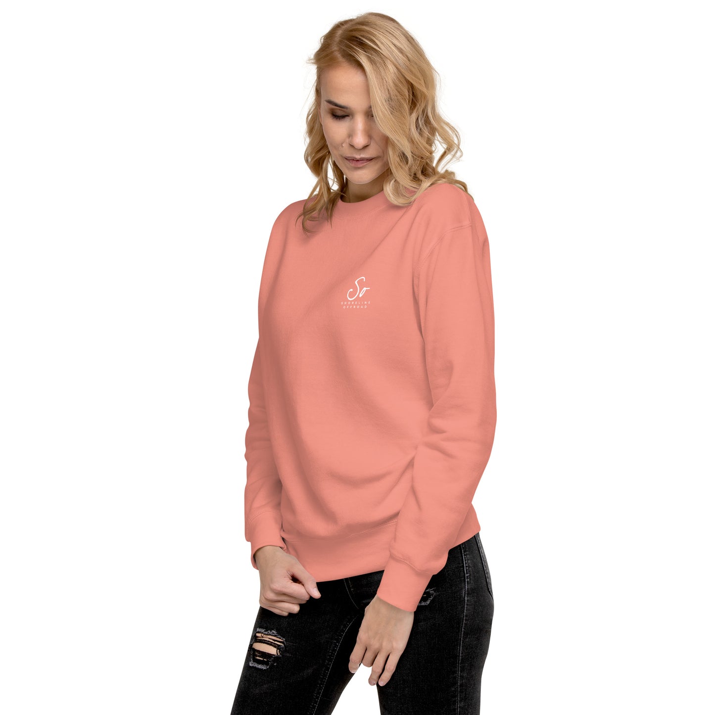 a woman wearing a pink sweatshirt and ripped jeans