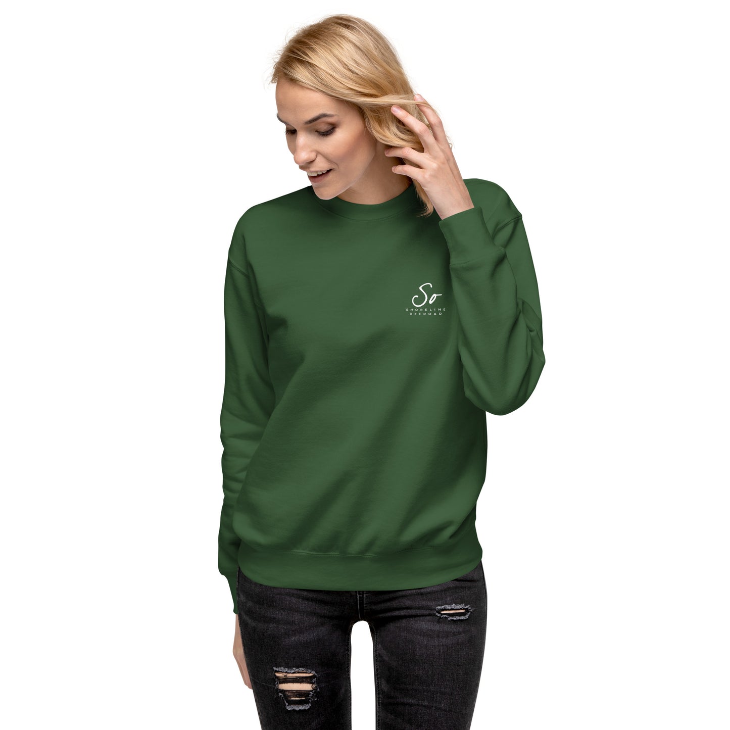 a woman wearing a green sweatshirt and ripped jeans