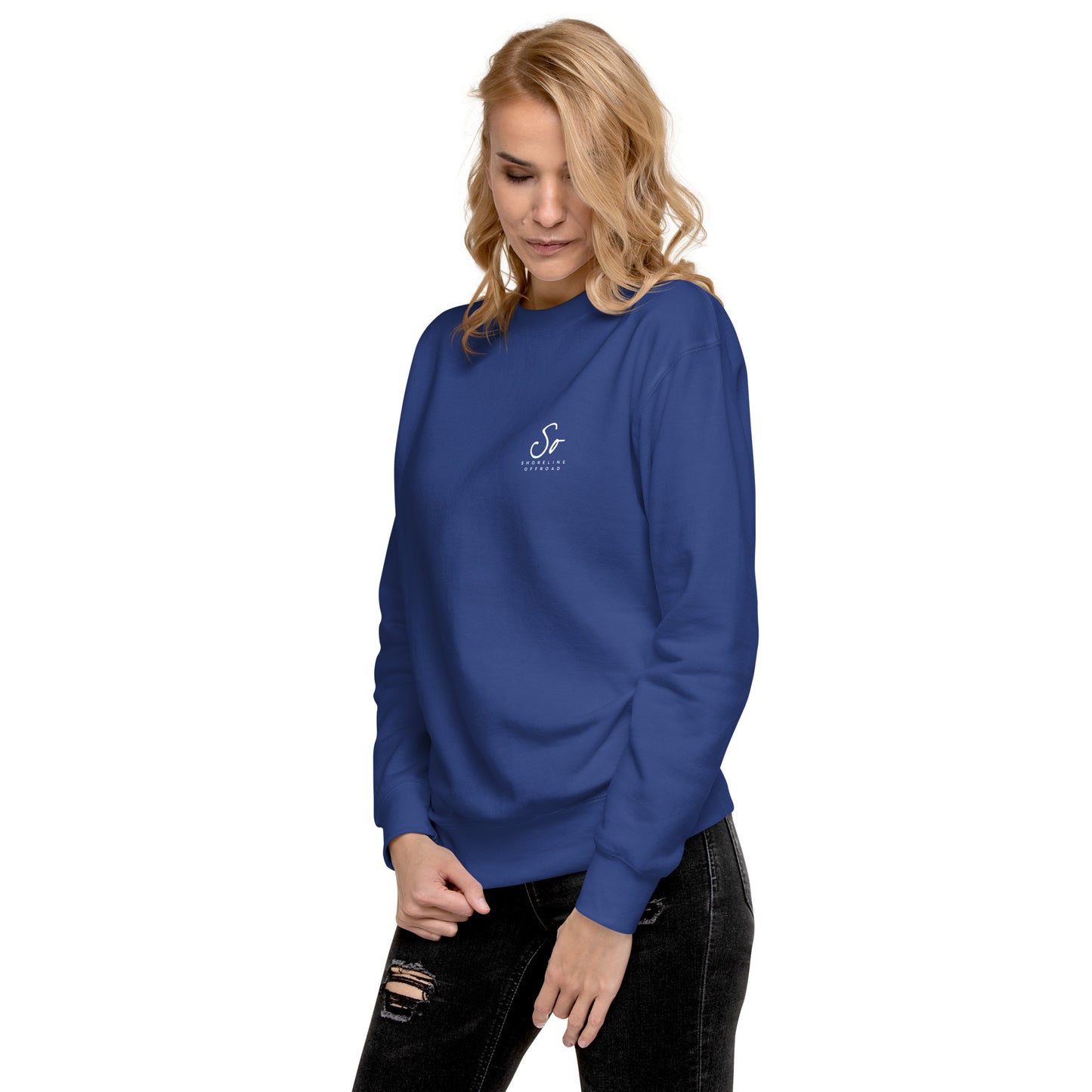 a woman wearing a blue sweatshirt and ripped jeans