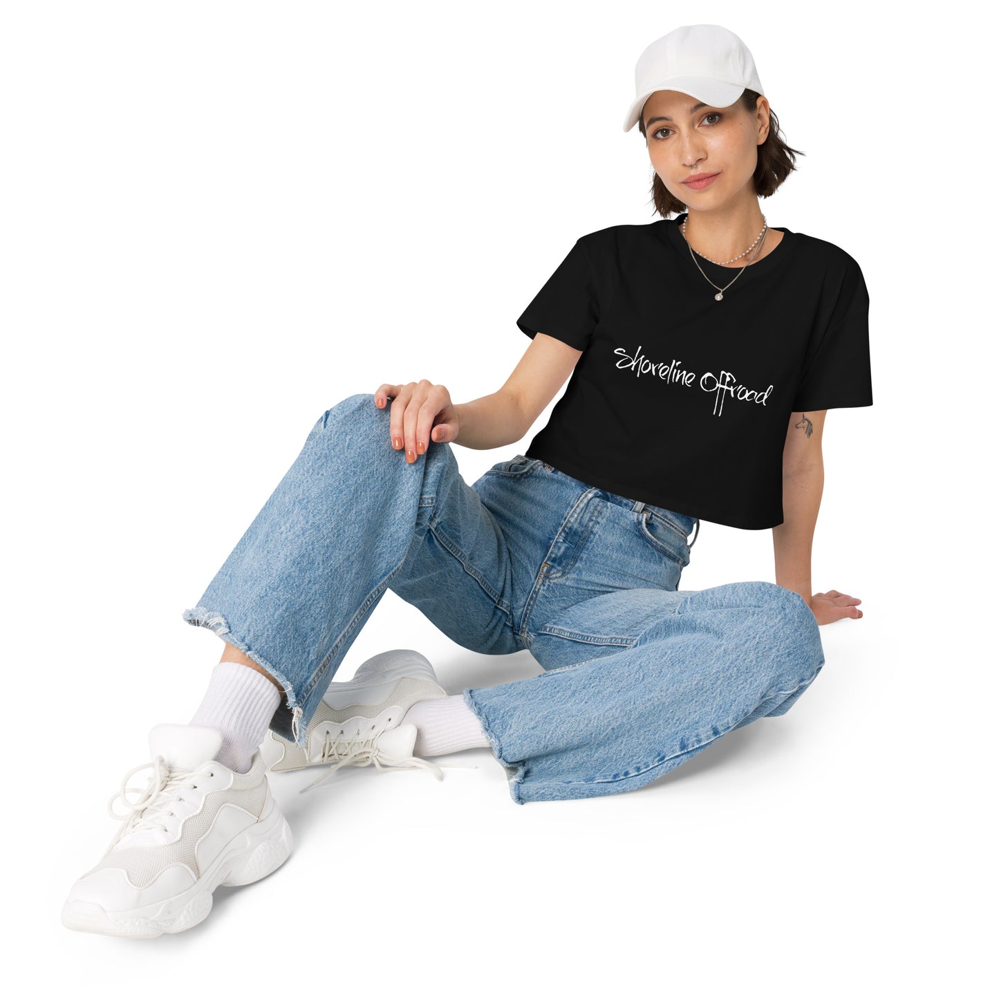 a woman sitting on the ground wearing a black shirt and jeans