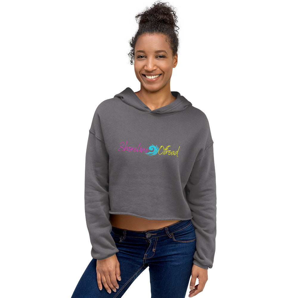 a woman wearing a grey crop top with a rainbow logo