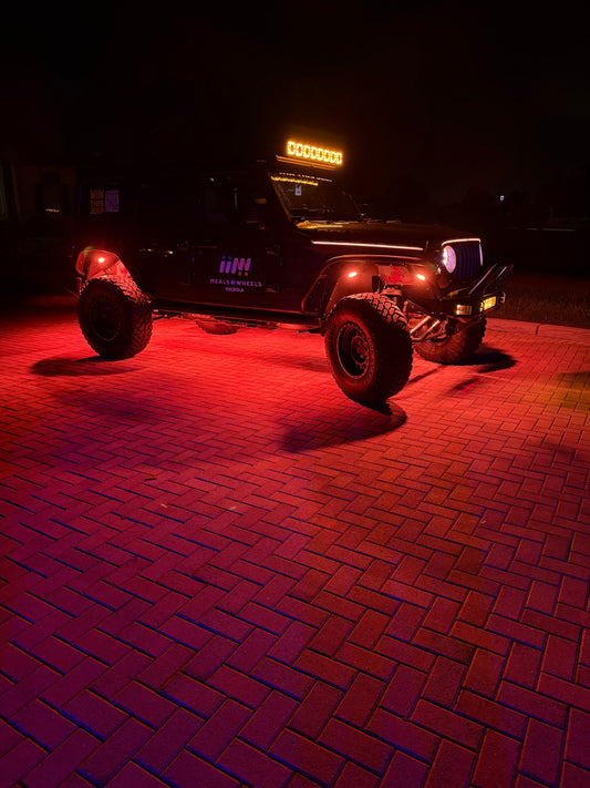 Custom raffle Jeep with Shoreline Offroad rock lights glowing red at night