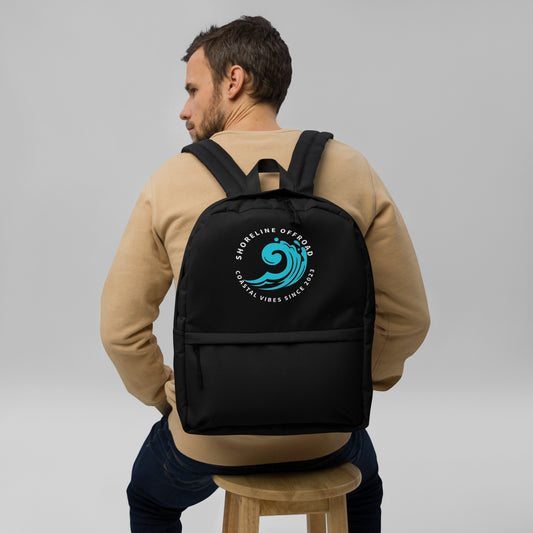 a man sitting on a stool wearing a black backpack