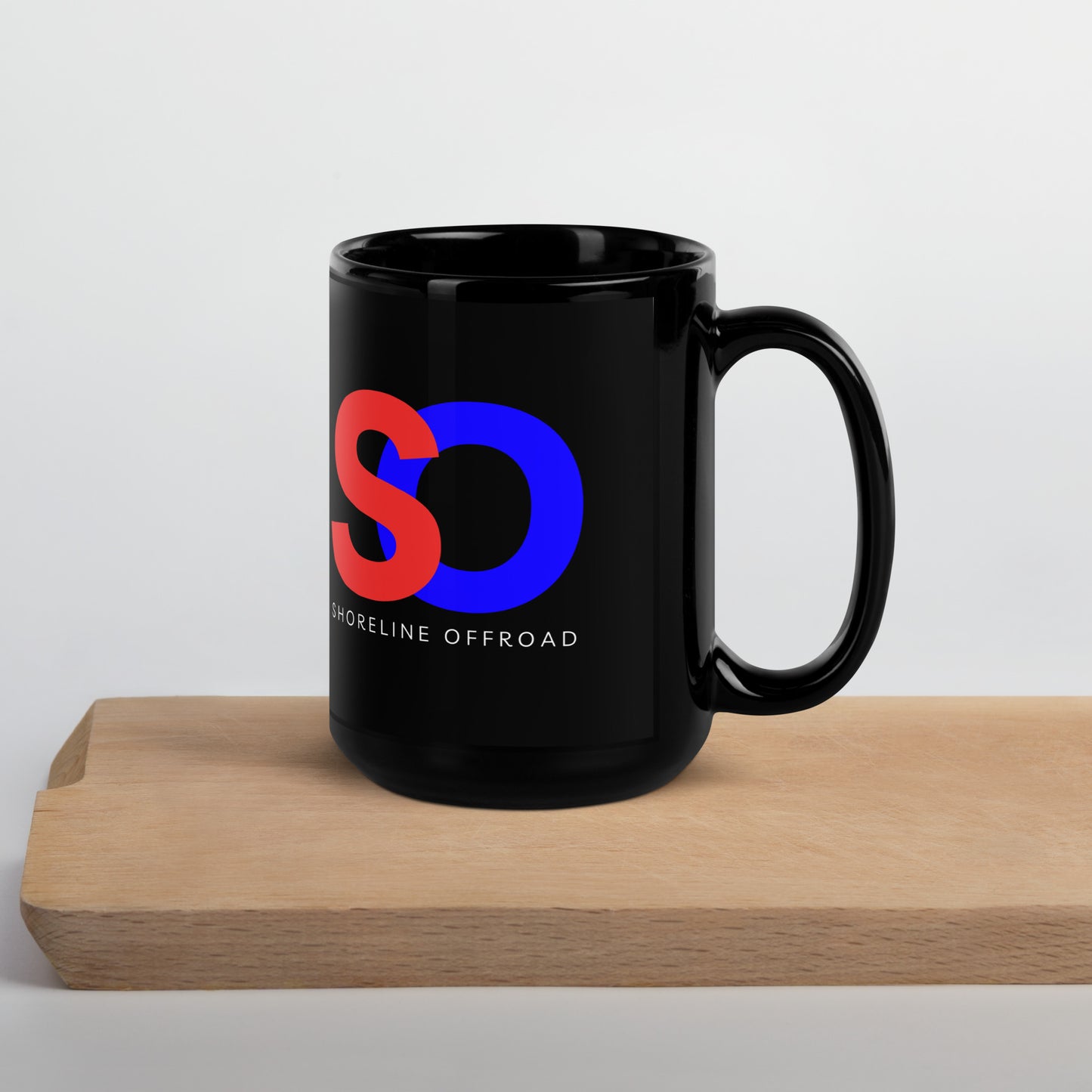 a black coffee mug sitting on top of a wooden table