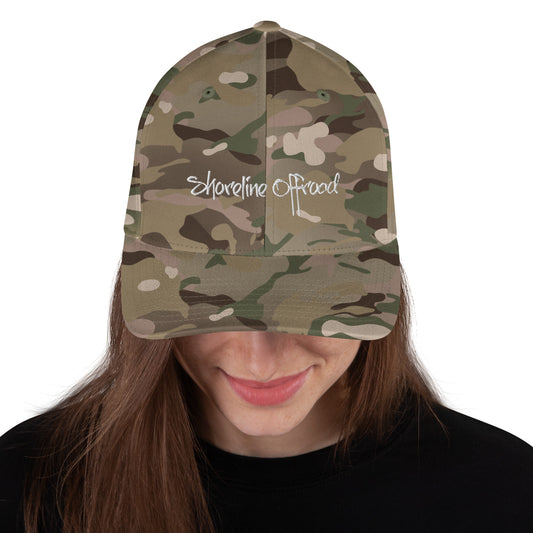 a woman wearing a camo hat with the word shoreline beach printed on it