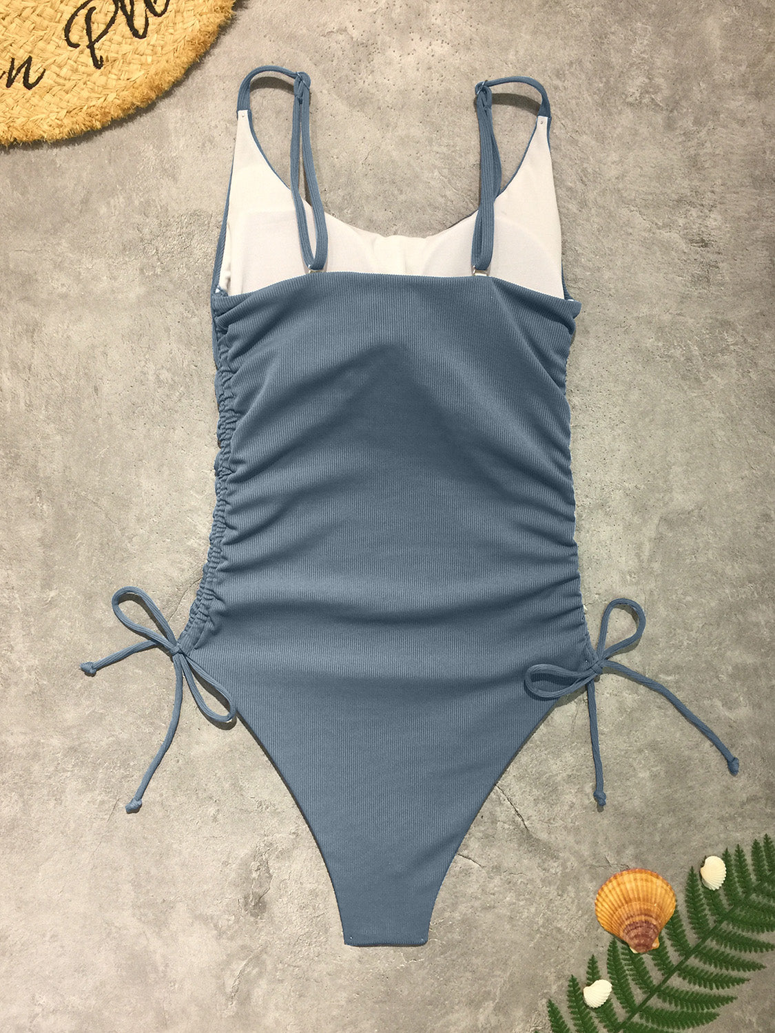 a blue and white one piece swimsuit sitting on the ground