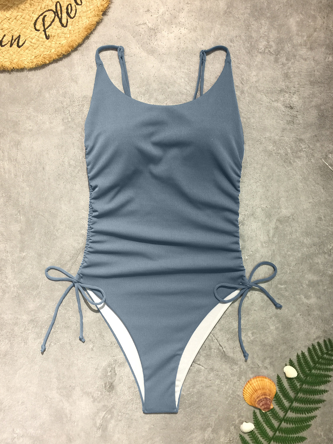 a women's blue and white swimsuit next to a straw hat