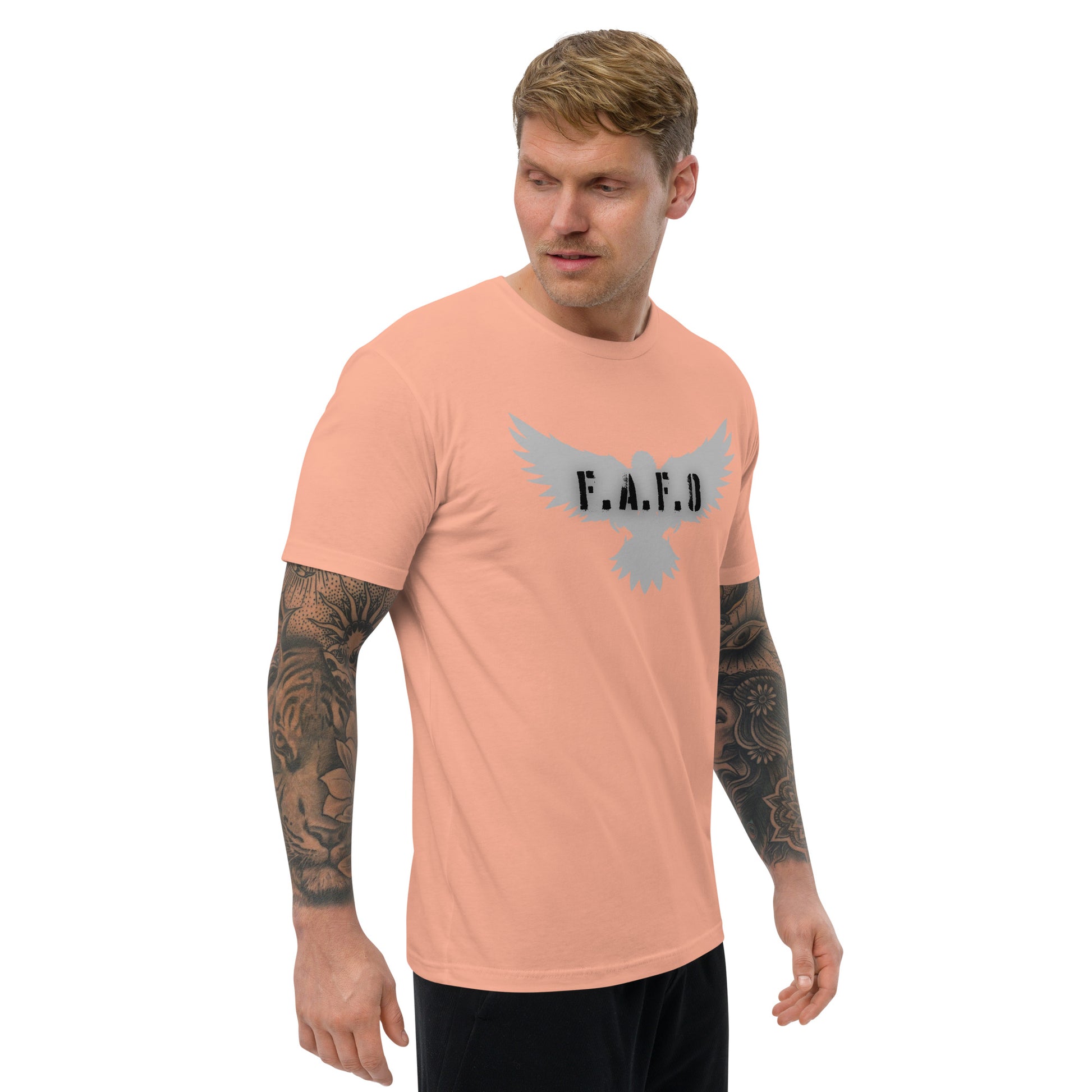 a man with a tattoo on his arm wearing a peach t - shirt