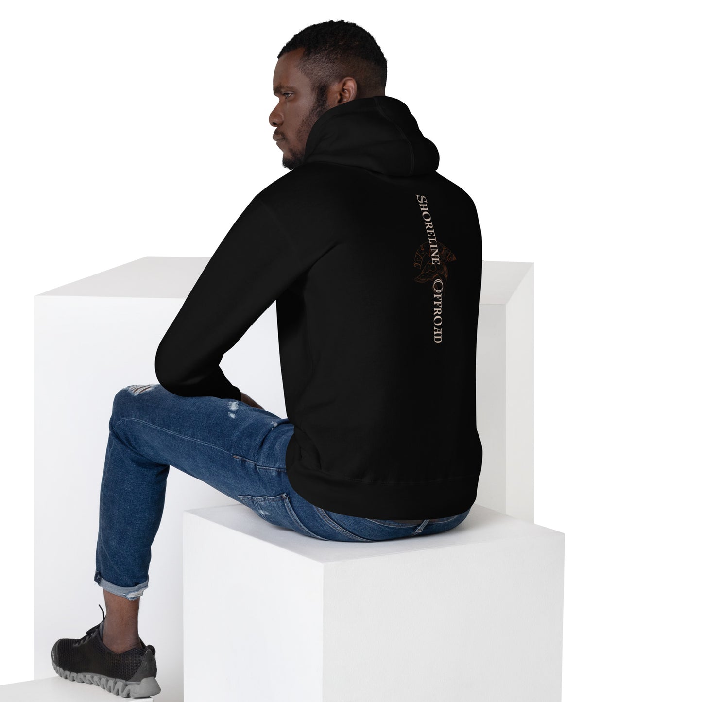 a man sitting on a white block wearing a black hoodie