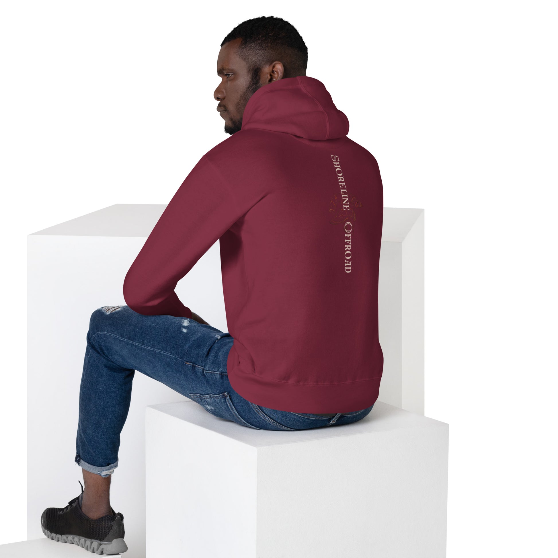 a man sitting on a block wearing a maroon hoodie