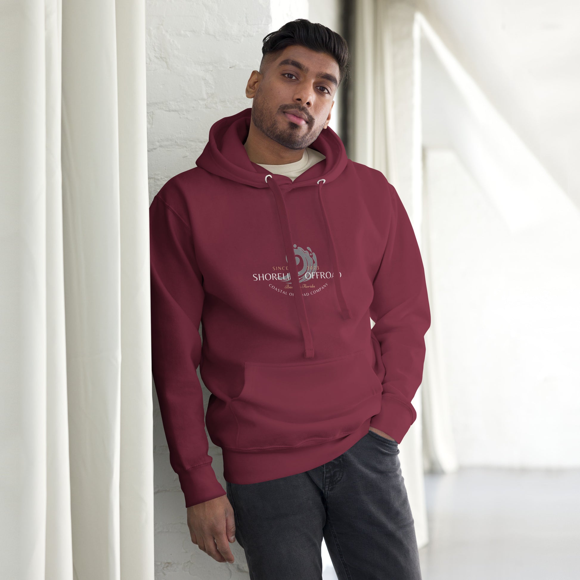 a man leaning against a wall wearing a red hoodie