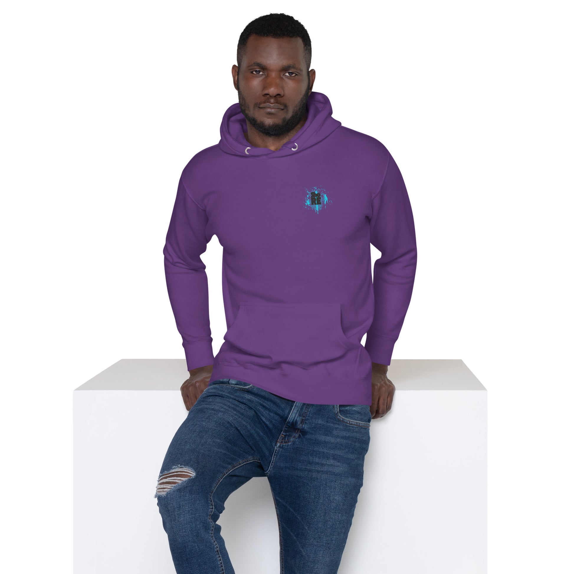 a man sitting on top of a white block wearing a purple hoodie