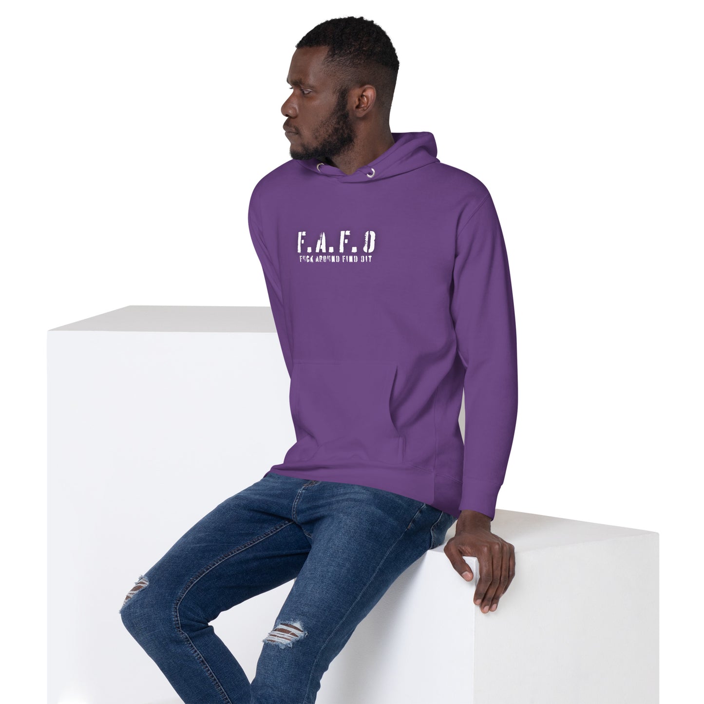 a man in a purple hoodie sitting on a white block