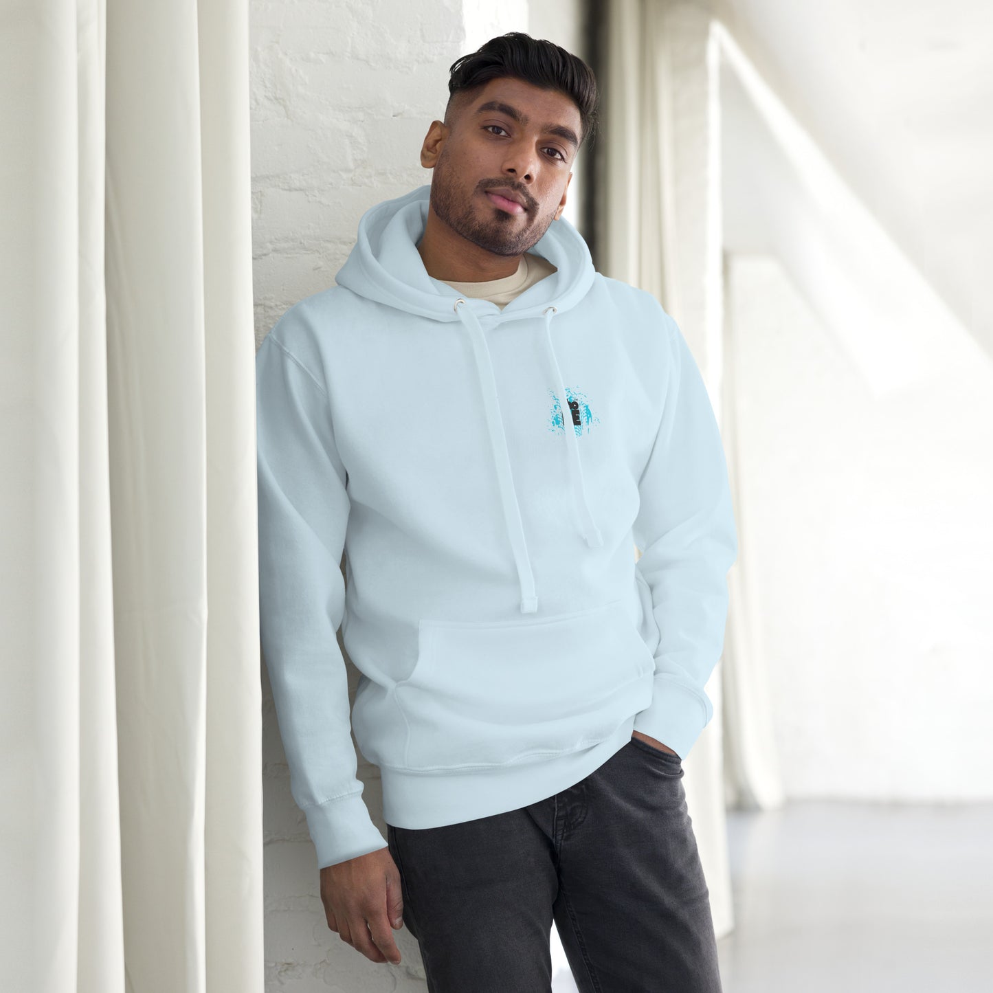 a man leaning against a wall wearing a blue hoodie