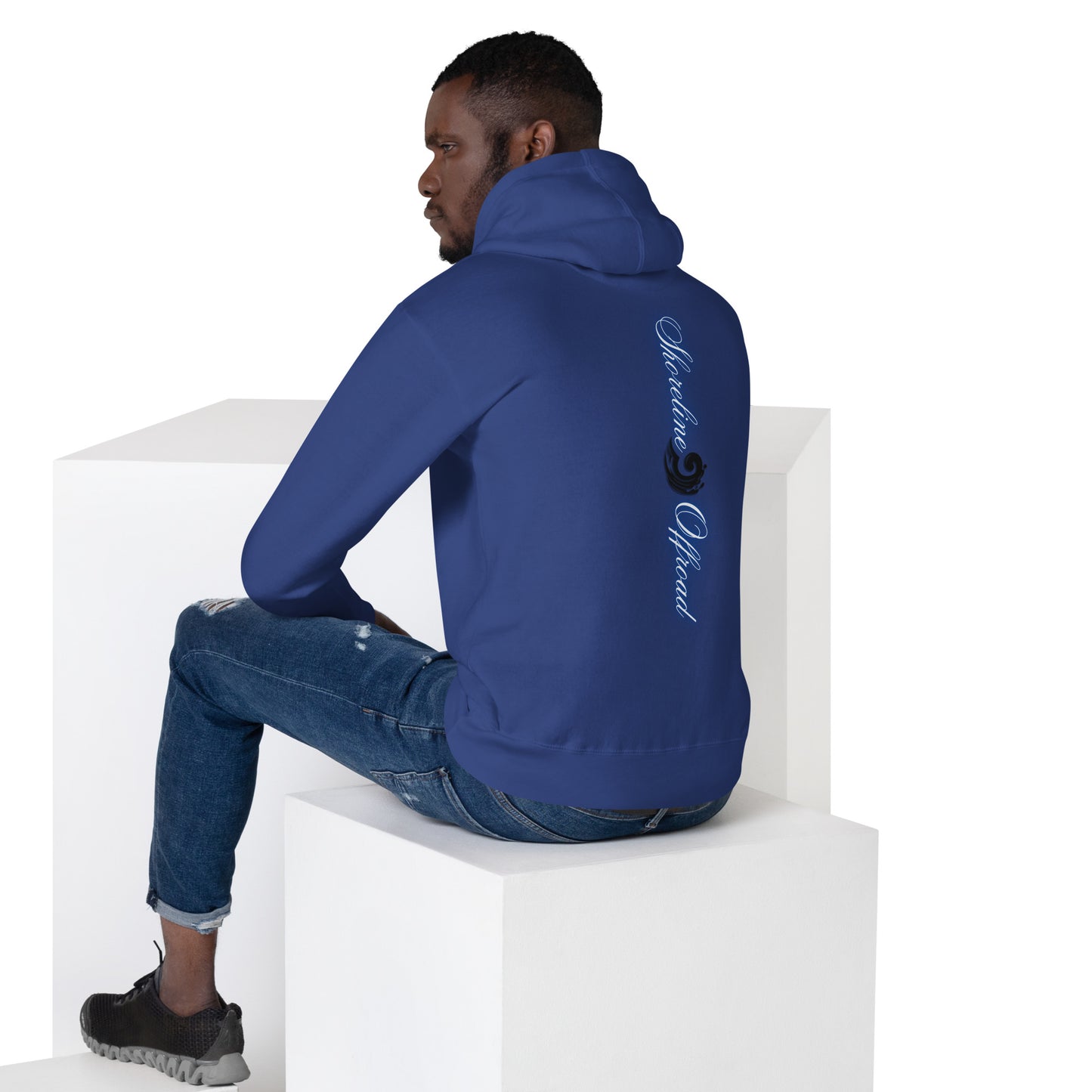 a man in a blue hoodie sitting on a white block