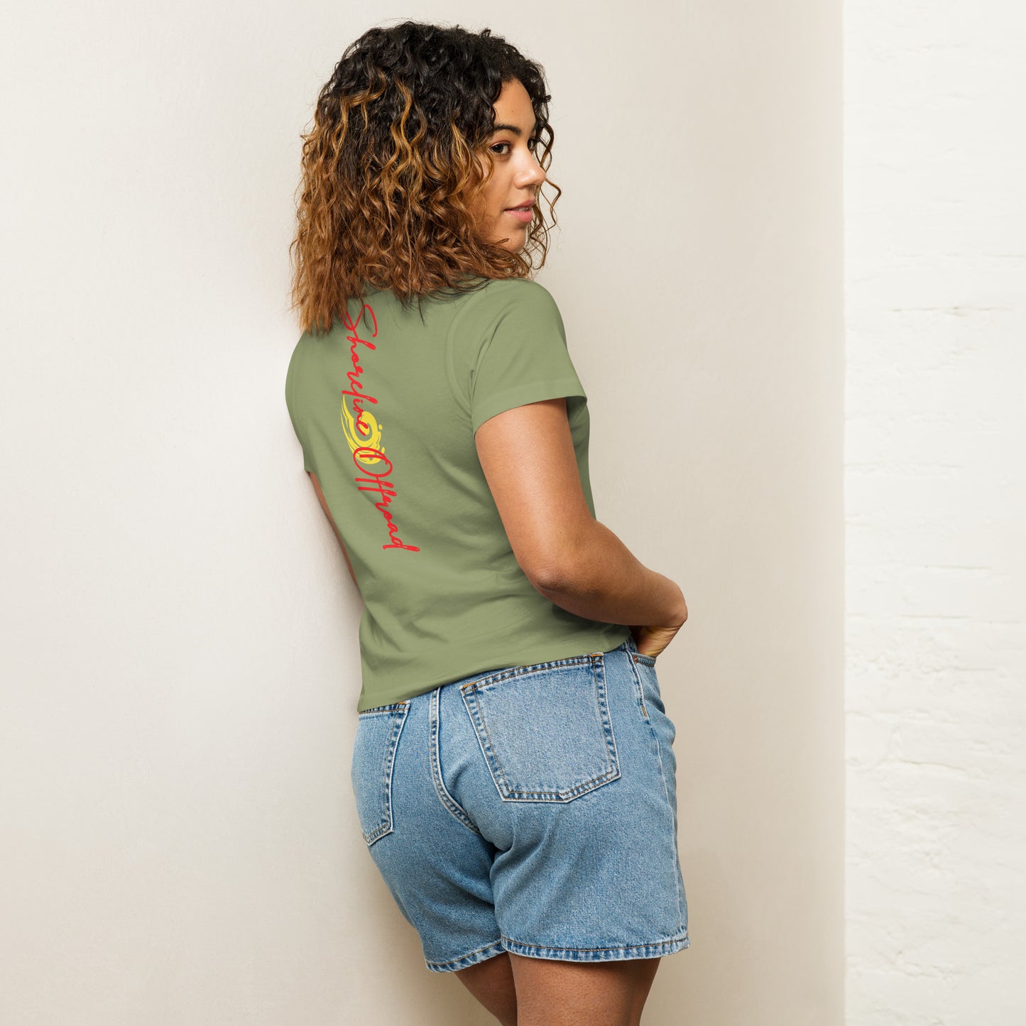 a woman in a green shirt is leaning against a wall