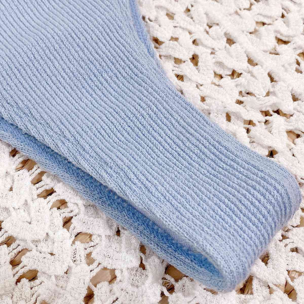a blue sweater laying on top of a white doily
