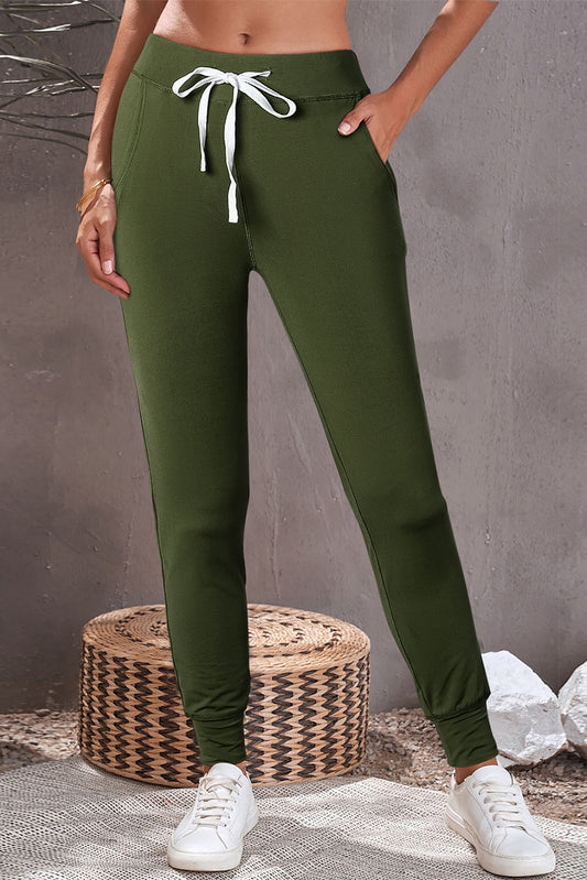 a woman wearing a crop top and green pants