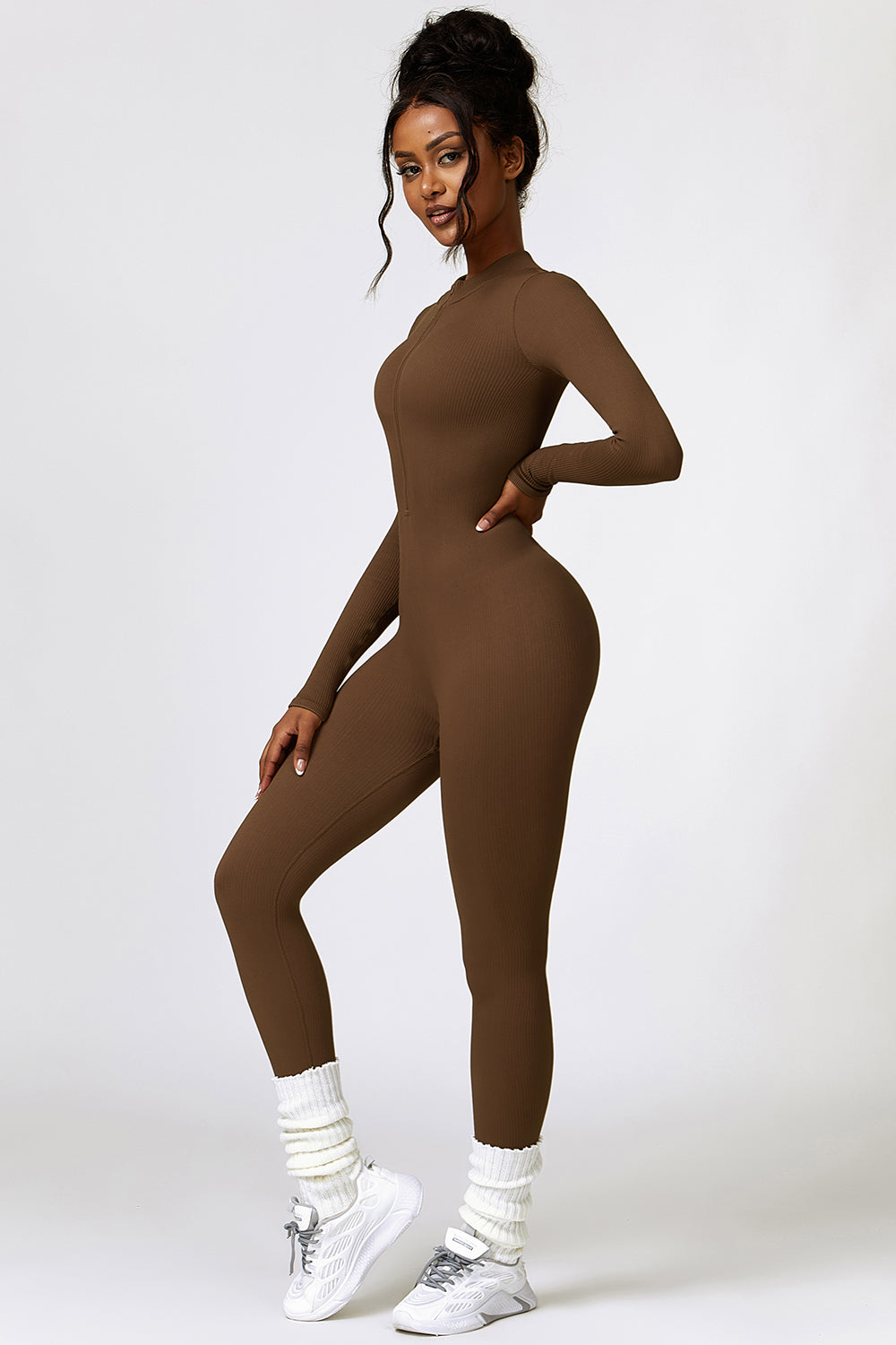 a woman in a brown bodysuit posing for a picture