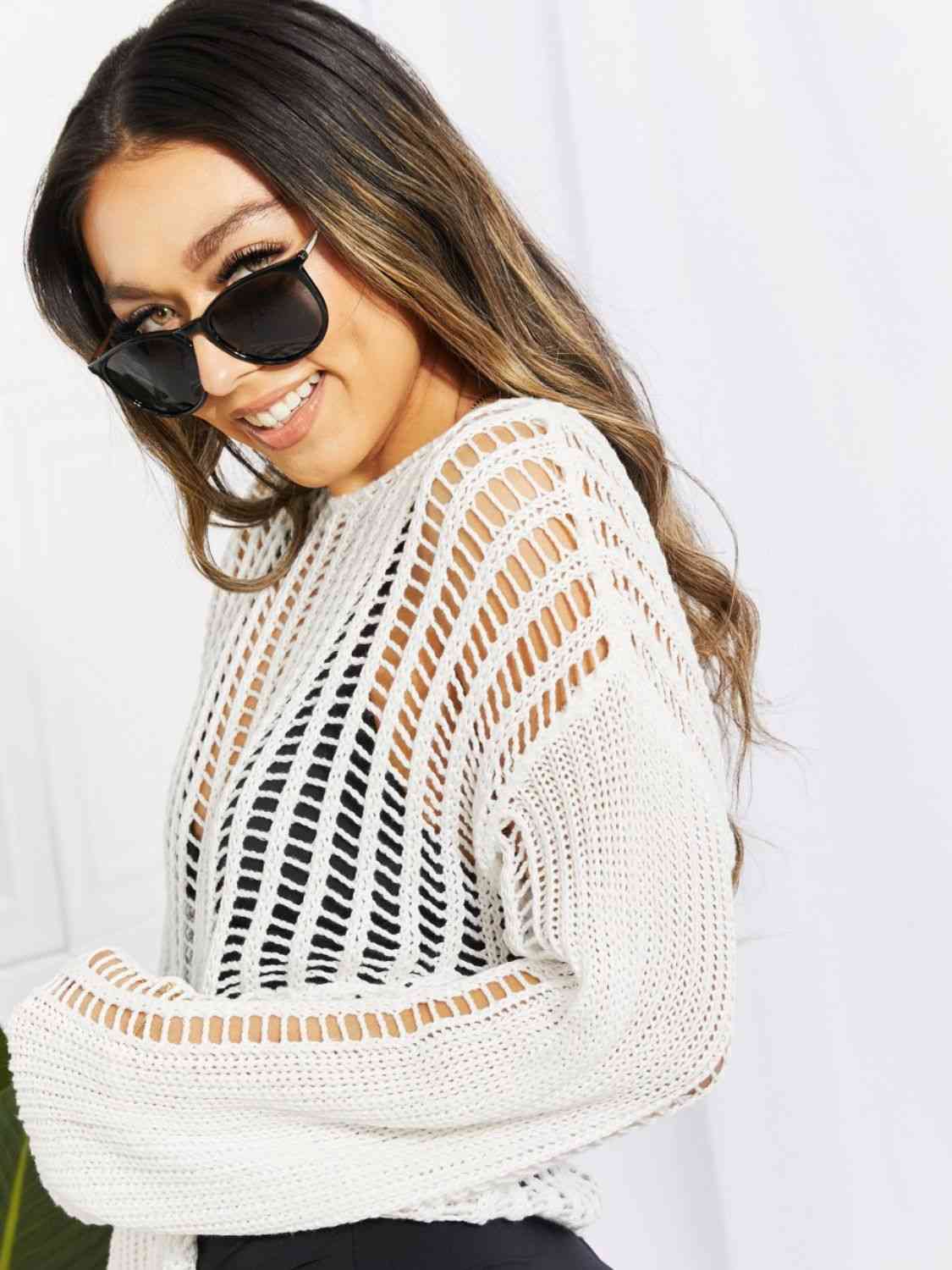 a woman wearing a white sweater and black sunglasses