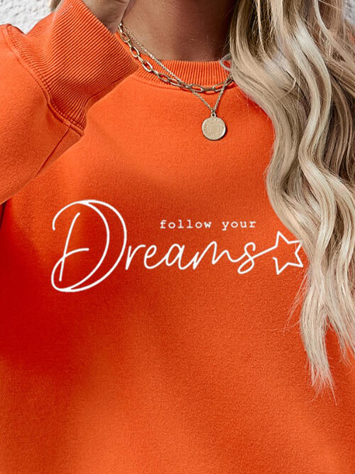 a woman wearing an orange sweatshirt that says follow your dreams
