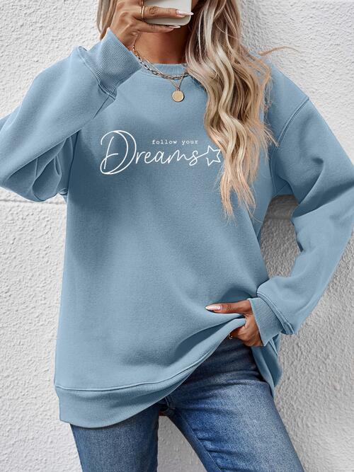 a woman wearing a blue sweatshirt with the words dream on it