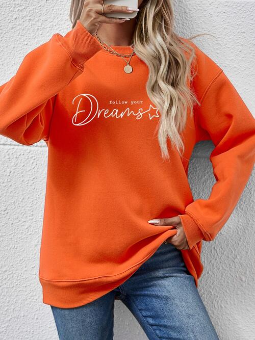 a woman wearing an orange sweatshirt and jeans