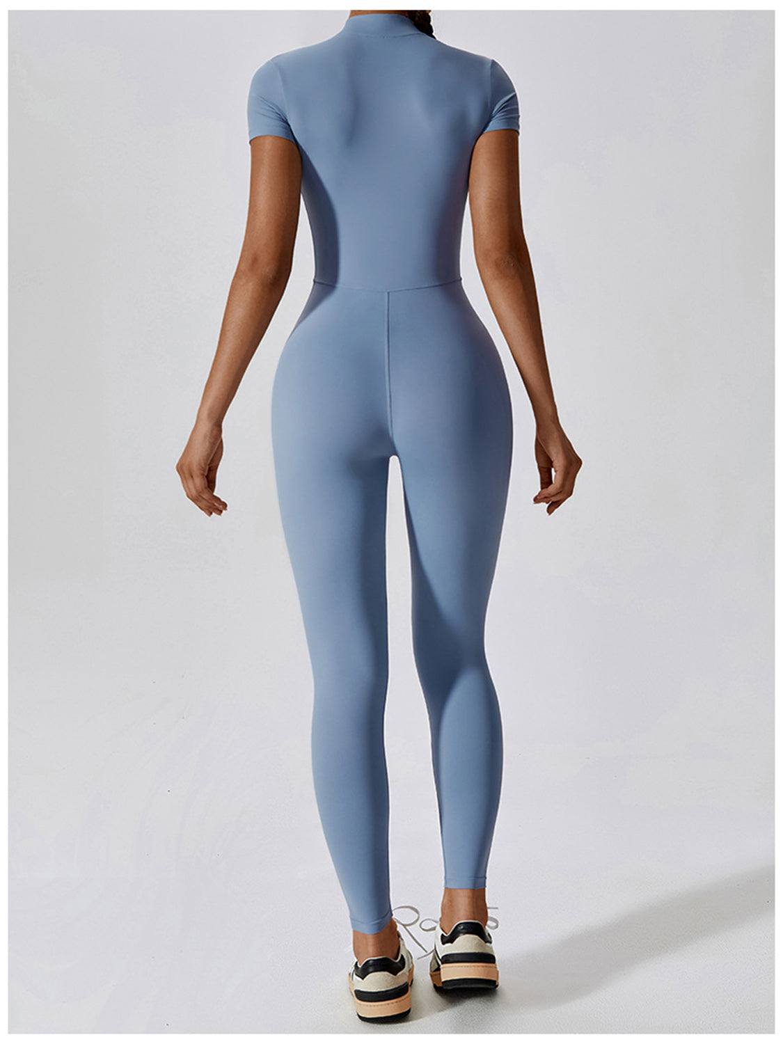 a woman in a blue bodysuit with her back to the camera