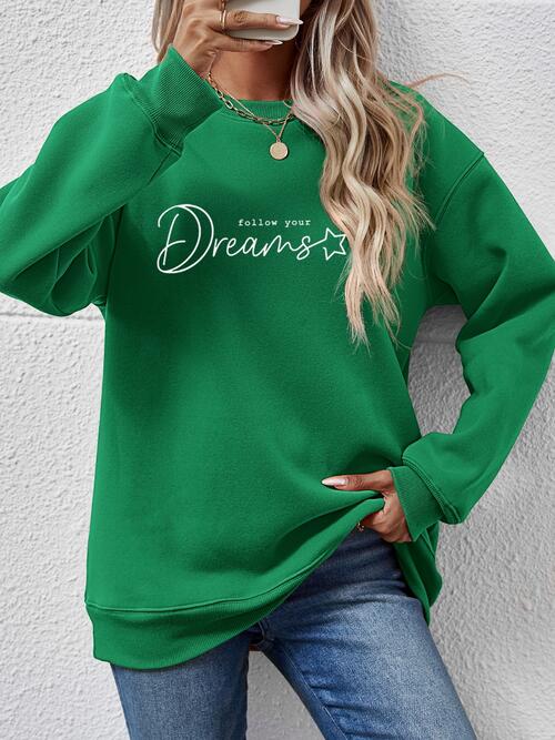 a woman wearing a green sweatshirt and jeans