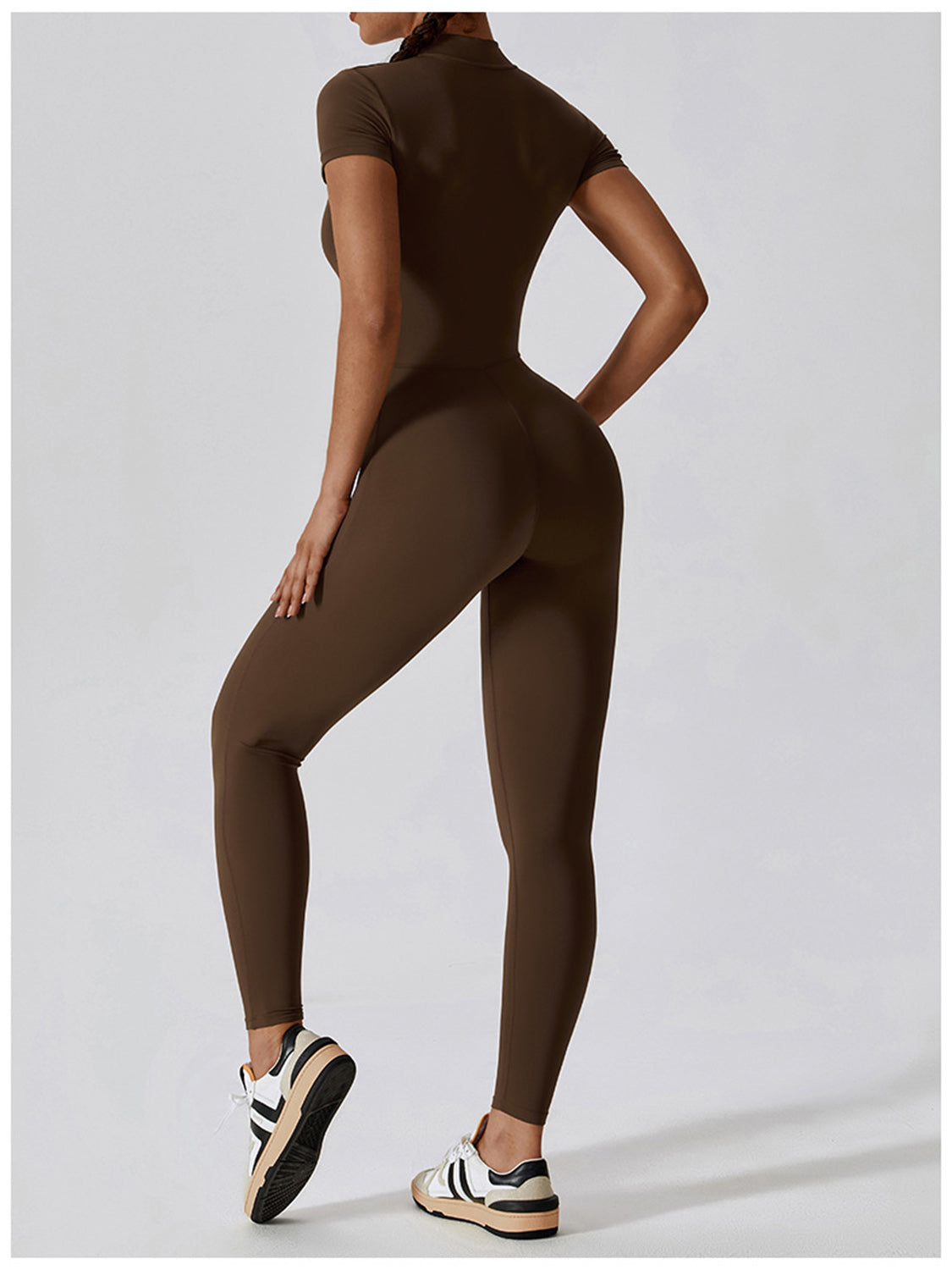 a woman in a brown bodysuit and sneakers