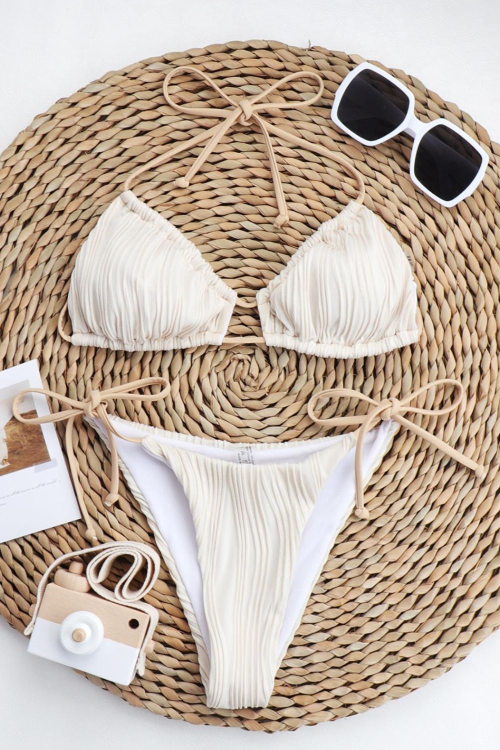 a woman's bikini top and sunglasses on a wicker mat