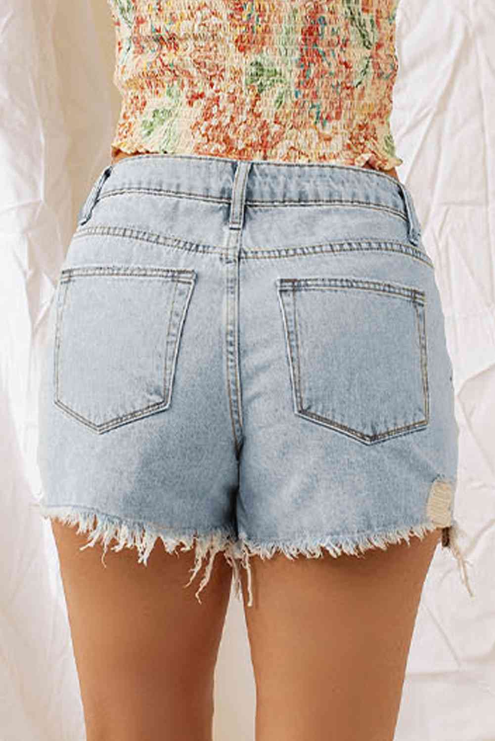 a woman in high waist denim shorts with a floral top